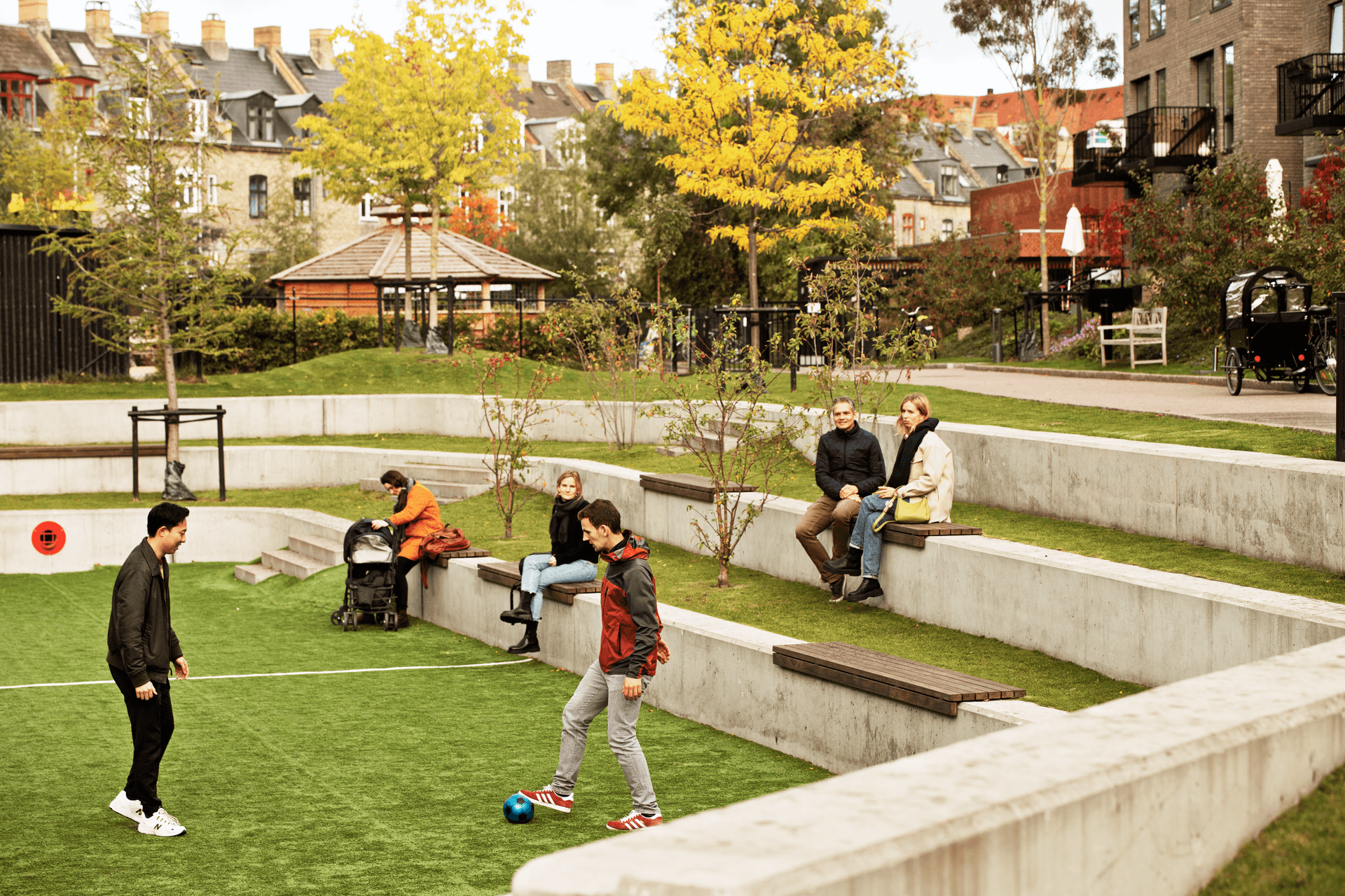 People relaxing at cloudburst park with football field 